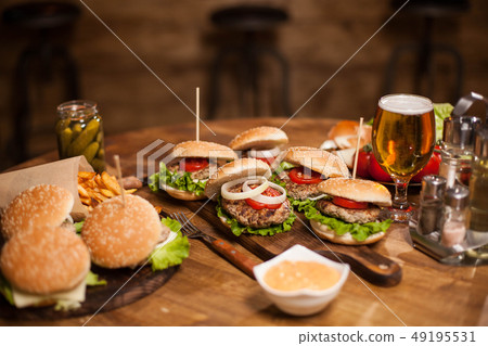 Lots of delicious burgers lying on a table Lots of delicious burgers lying on a table 49195531