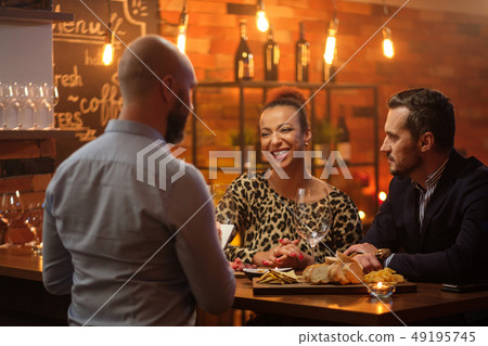 Couple talking to bartender behind bar counter in a cafe Couple talking to bartender behind bar counter in a cafe 49195745