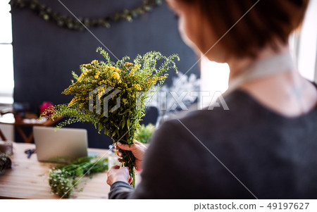 Midsection of young creative woman in a flower shop. A startup of florist business. Midsection of young creative woman in a flower shop. A startup of florist business. 49197627