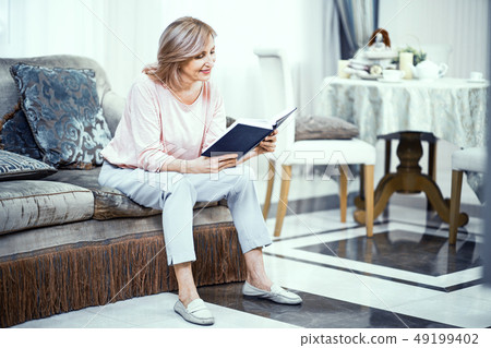 Middle Aged Woman Sitting On Sofa And Reading Bible Middle Aged Woman Sitting On Sofa And Reading Bible 49199402