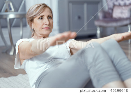 Cheerful mature woman making yoga press exercises Cheerful mature woman making yoga press exercises 49199648