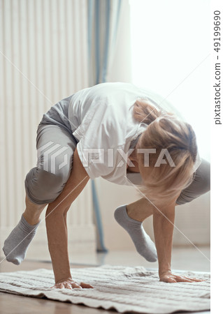 Cheerful mature woman making yoga exercises Cheerful mature woman making yoga exercises 49199690