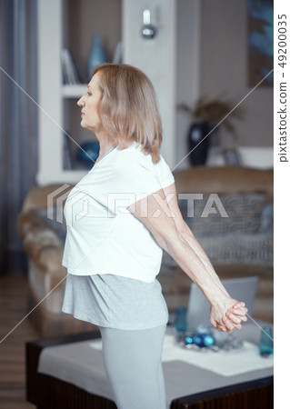 Middle aged woman doing yoga at home 49200035