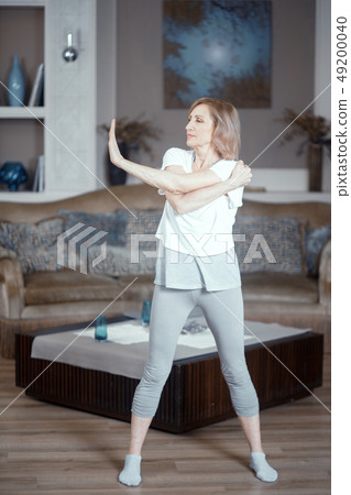 A 50 Year Old Woman Practices Yoga at Home in the Living Room. A 50 Year Old Woman Practices Yoga at Home in the Living Room. 49200040