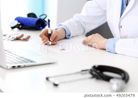 Female doctor filling up prescription form while sitting at the desk in hospital closeup. Healthcare 49203479