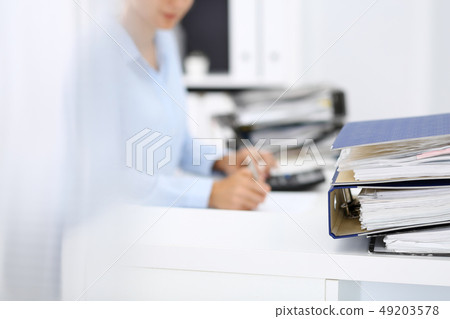 Binders with papers are waiting to be processed by business woman or bookkeeper back in blur 49203578