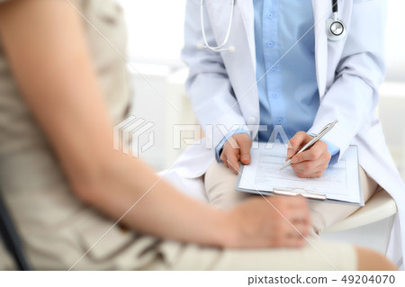 Doctor and patient talking. Physician at work in hospital while writing up medication history 49204070