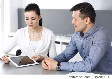 Cheerful smiling businessman and woman working with tablet computer in modern office. Headshot at 49204521
