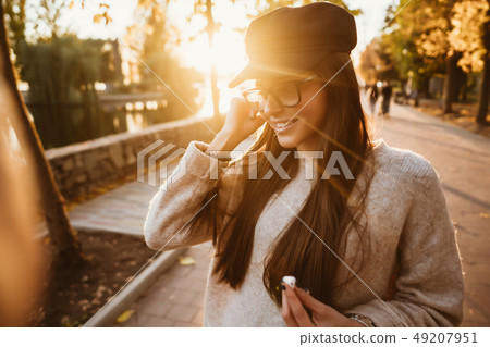 Beautiful young girl listening to music in the park through a wireless earpiece 49207951