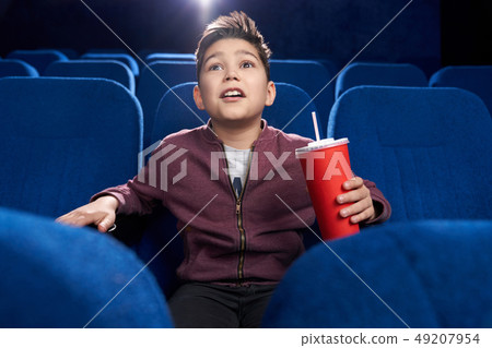 Fascinated teenager watching movie attentively in cinema. Fascinated teenager watching movie attentively in cinema. 49207954