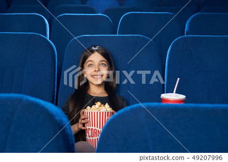 Beautiful, happy girl watching movie with popcorn in cinema. Beautiful, happy girl watching movie with popcorn in cinema. 49207996