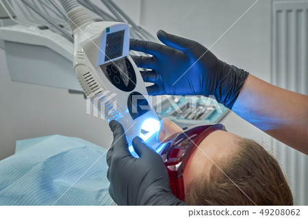 Woman lying on chair during procedure of whitening of teeth 49208062