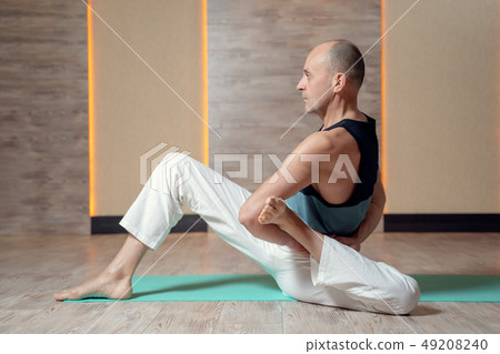 Man yogi trains sitting on blue mat. Man yogi trains sitting on blue mat. 49208240