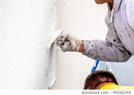 Construction worker plastering and smoothing concrete wall with cement Construction worker plastering and smoothing concrete wall with cement 49208249