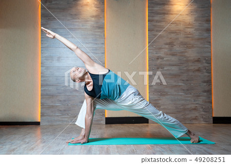 Athletic man looking up with raised arm doing yoga on blue mat. Athletic man looking up with raised arm doing yoga on blue mat. 49208251
