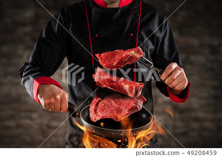 Closeup of chef throwing raw beef steaks Closeup of chef throwing raw beef steaks 49208459