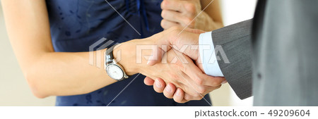 Businessman and woman shake hands as hello in office closeup Businessman and woman shake hands as hello in office closeup 49209604