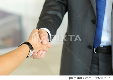 Businessman and woman shake hands as hello in office closeup Businessman and woman shake hands as hello in office closeup 49209606