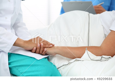 Friendly female medicine doctor's hands holding pregnant woman's hand Friendly female medicine doctor's hands holding pregnant woman's hand 49209688