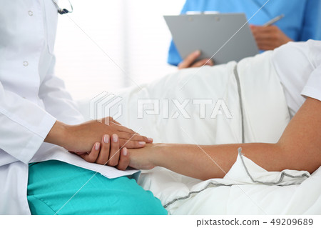 Friendly female doctor's hands holding patient's hand Friendly female doctor's hands holding patient's hand 49209689