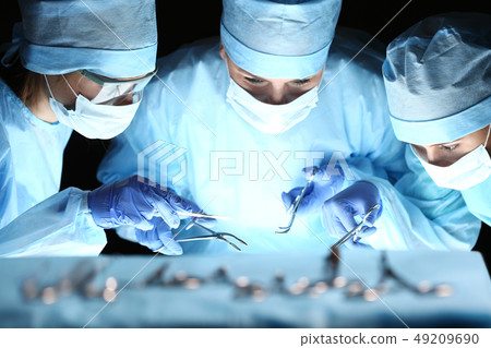 Group of surgeons at work operating in surgical theatre Group of surgeons at work operating in surgical theatre 49209690