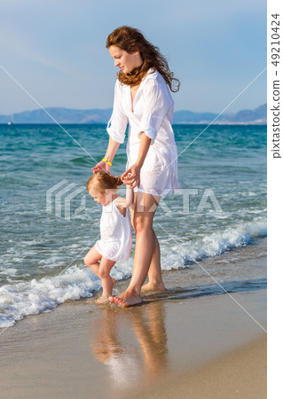 Mother and daughter walking on the beach 49210424