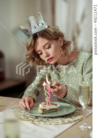 Woman wearing gold ring earrings burning the candle on cake Woman wearing gold ring earrings burning the candle on cake 49211471