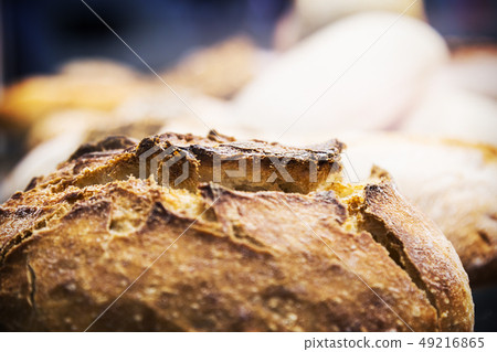 freshly baked loaf of bread with an appetizing crust in the foreground  49216865