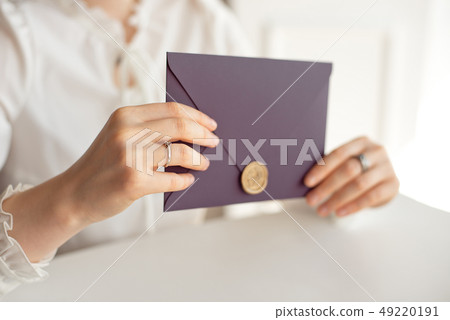 Close-up woman with slim body holding in hands the invitation card purple color square shape Close-up woman with slim body holding in hands the invitation card purple color square shape 49220191
