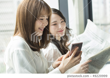 讀報紙的兩名婦女在窗口邊 49220999