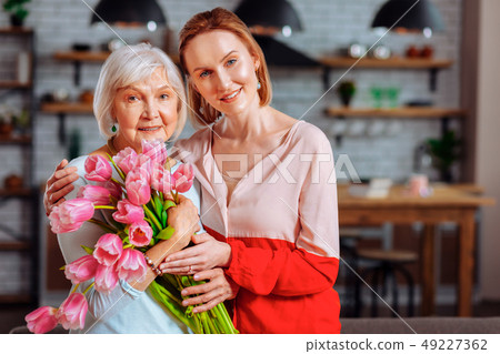 Attractive daughter posing with silver-haired mother with tulips bouquet 49227362