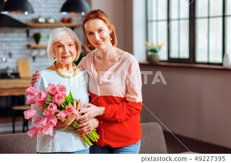 Elegant dame with pink tulips being cuddled by beautiful daughter-in-law. 49227395