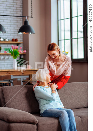 Lovely young-adult lady softly putting hand on mother shoulder 49227450