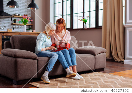 Elderly female sitting on sofa with her young-adult daughter 49227592
