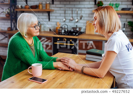Pleasant granny sharing her grief with young-adult understanding lady 49227652
