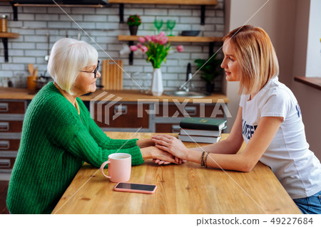 Upset sorrowful pensioner expressing emotions while talking to young lady 49227684
