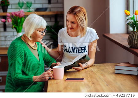 Captivating young-adult female engaging in Bible reading with focused granny 49227719