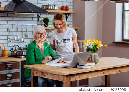 Smiling aging female and volunteer having conversation about documents filling 49227998