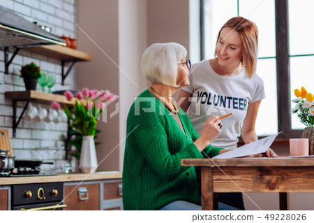 Elegant dame discussing with young girl the papers at kitchen 49228026