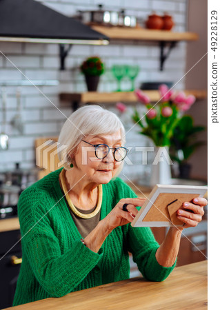 Septuagenarian lady viewing photo of her family in frame 49228129