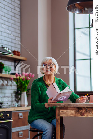 Beautiful granny smiling to someone calling while keeping a book 49228286