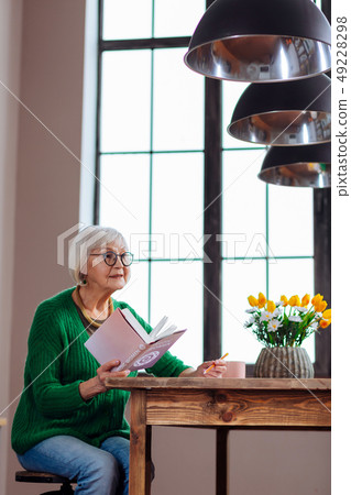 Charming granny responding to someone calling holding book in hand Charming granny responding to someone calling holding book in hand 49228298