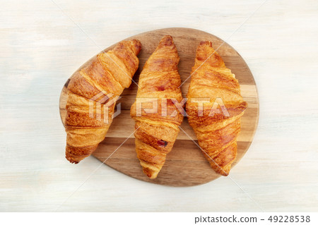 A high key photo of croissants, shot from above on a white wooden background with a place for text A high key photo of croissants, shot from above on a white wooden background with a place for text 49228538