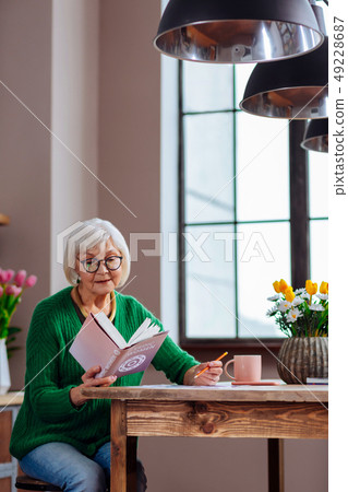 Cheerful old lady writing down vedic books main points 49228687