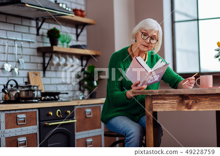 Smart white-haired lady in years making notes of vedic books 49228759