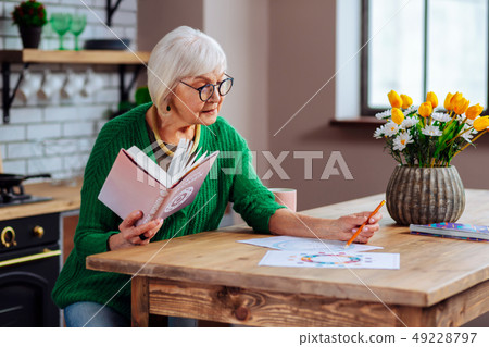 Elderly female trying to understand vedic charts using book 49228797