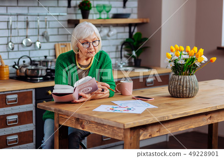 Focused aged white-haired female considering vedic book and making notes Focused aged white-haired female considering vedic book and making notes 49228901
