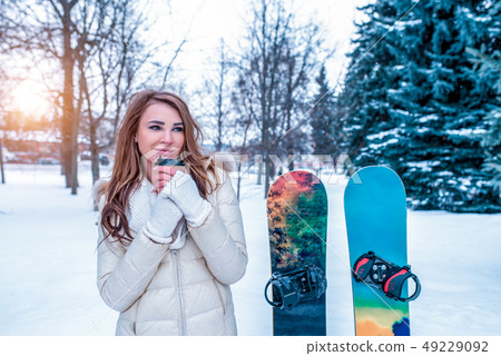 The girl with long hair in winter in the forest. Warms in his hands holding a cup of coffee tea 49229092