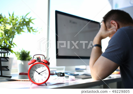 Red alarm clock stand at worktable with thoughtful man 49229805