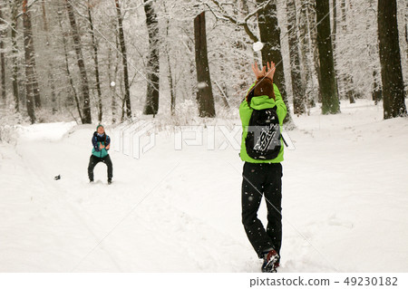 Beautiful happy couple throwing snowballs and having fun in winter park 49230182
